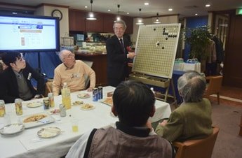 懇親会の途中で囲碁講義が始まる場面も